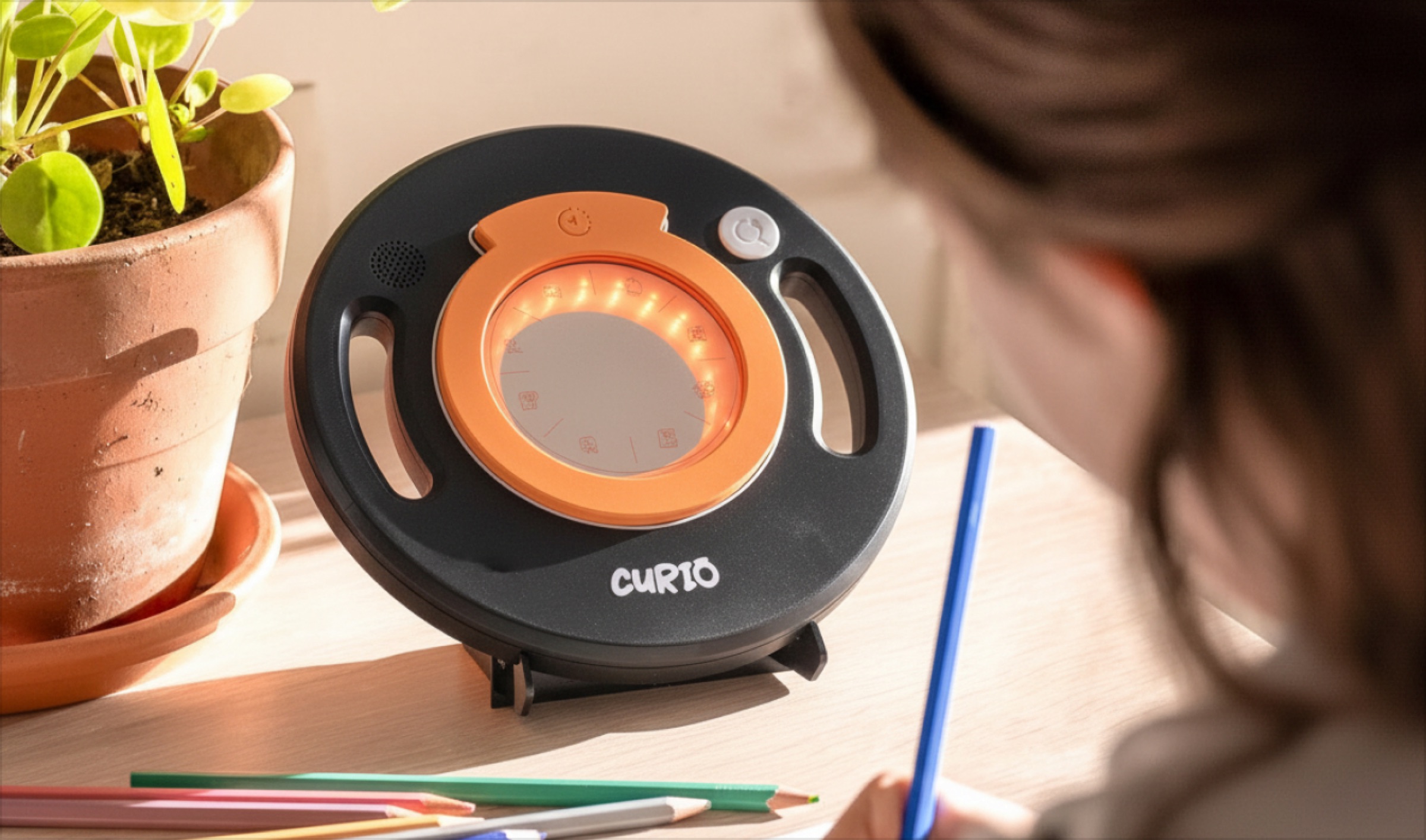 Curio on a desk with a lens snapped on and its ring lit, the other lenses beside it