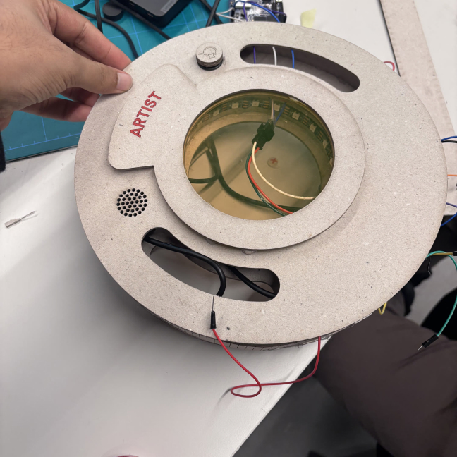 A grey 3D-printed Curio with an Artist lens, wires running into the ring